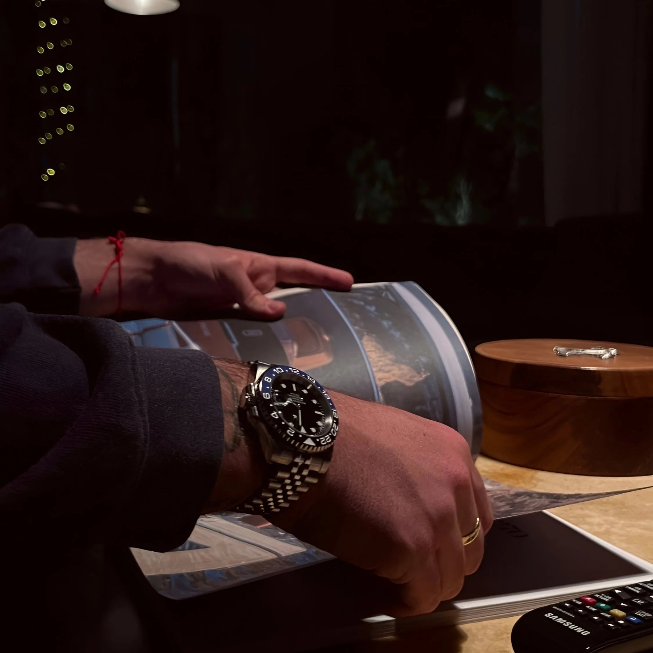 GMTEIKO Batman von Seiko Moddys – handgefertigter Seiko Mod im GMT-Master II Batman Stil mit schwarz-blauer Lünette, getragen am Handgelenk beim Lesen eines Magazins.