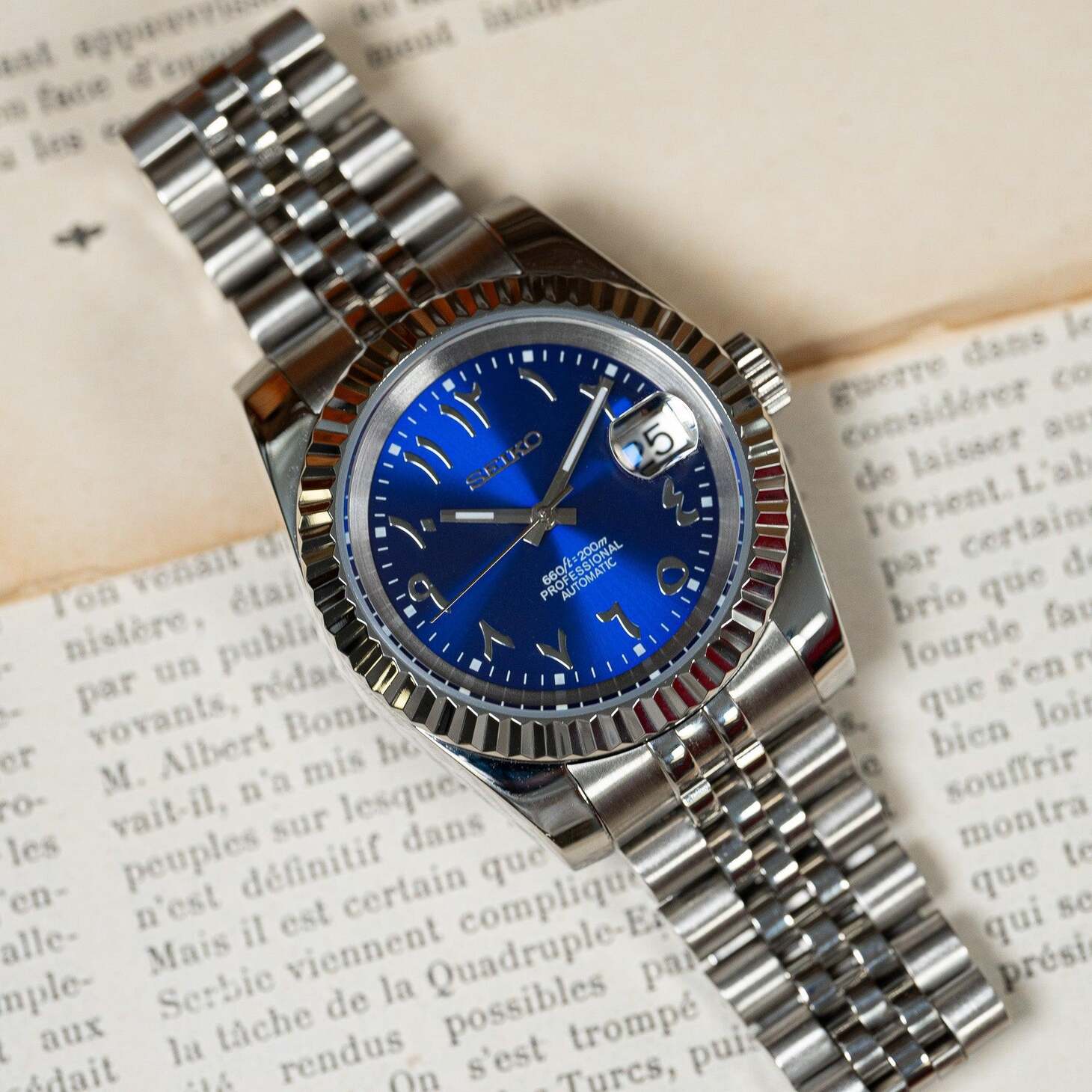 Seiko Mod Datejust Royal Blue Arabic front view on vintage paper background showing metal bracelet