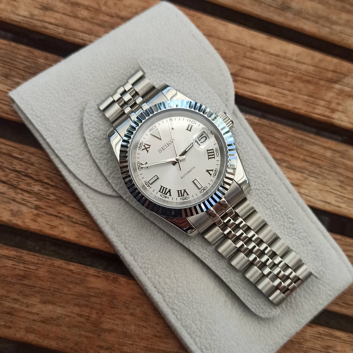 Silver dial Seiko Mod Datejust with Roman numerals displayed on suede pad