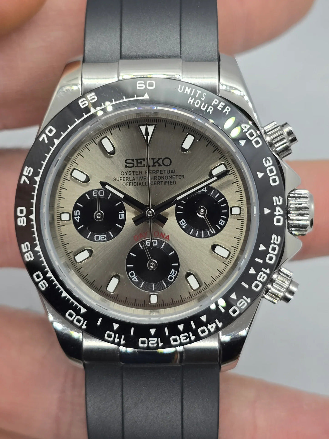 Front view of Seiko Mod Daytona with champagne dial, black ceramic bezel, and black rubber strap.