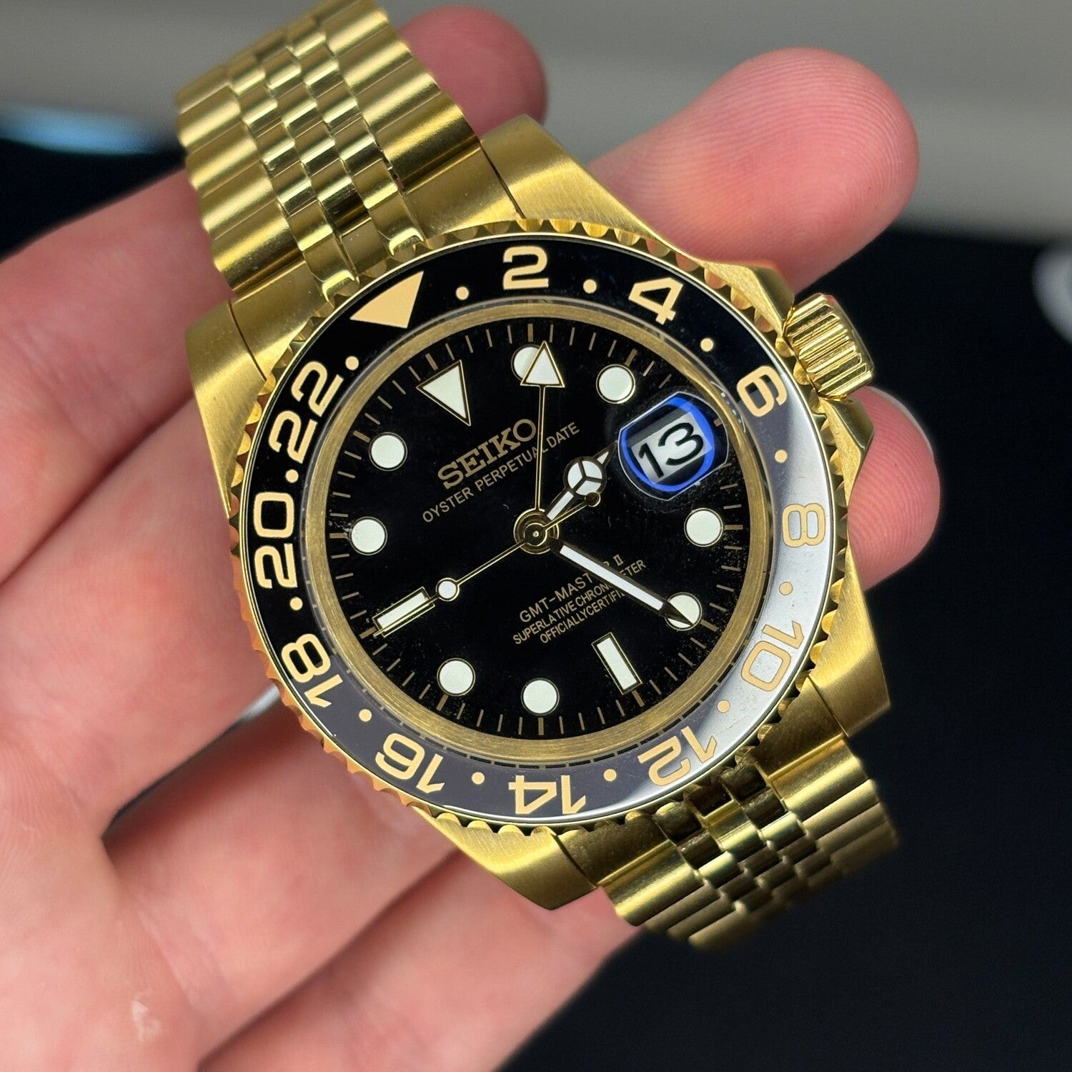 Close up Seiko Mod GMT Gold showing black dial gold accents and ceramic bezel reflection
