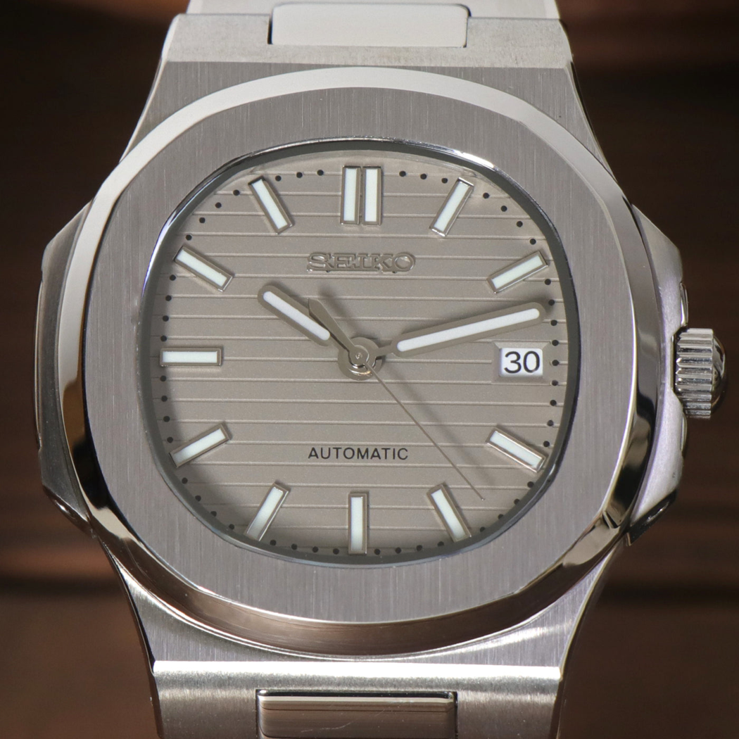 Close up of Seiko mod Nautilus cream dial with horizontal pattern and date window at three o’clock