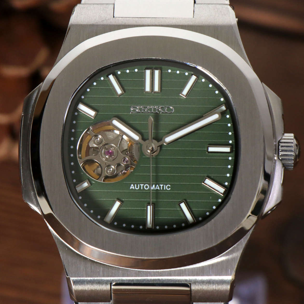 Close up of Seiko mod Nautilus olive green open heart dial revealing balance wheel through aperture