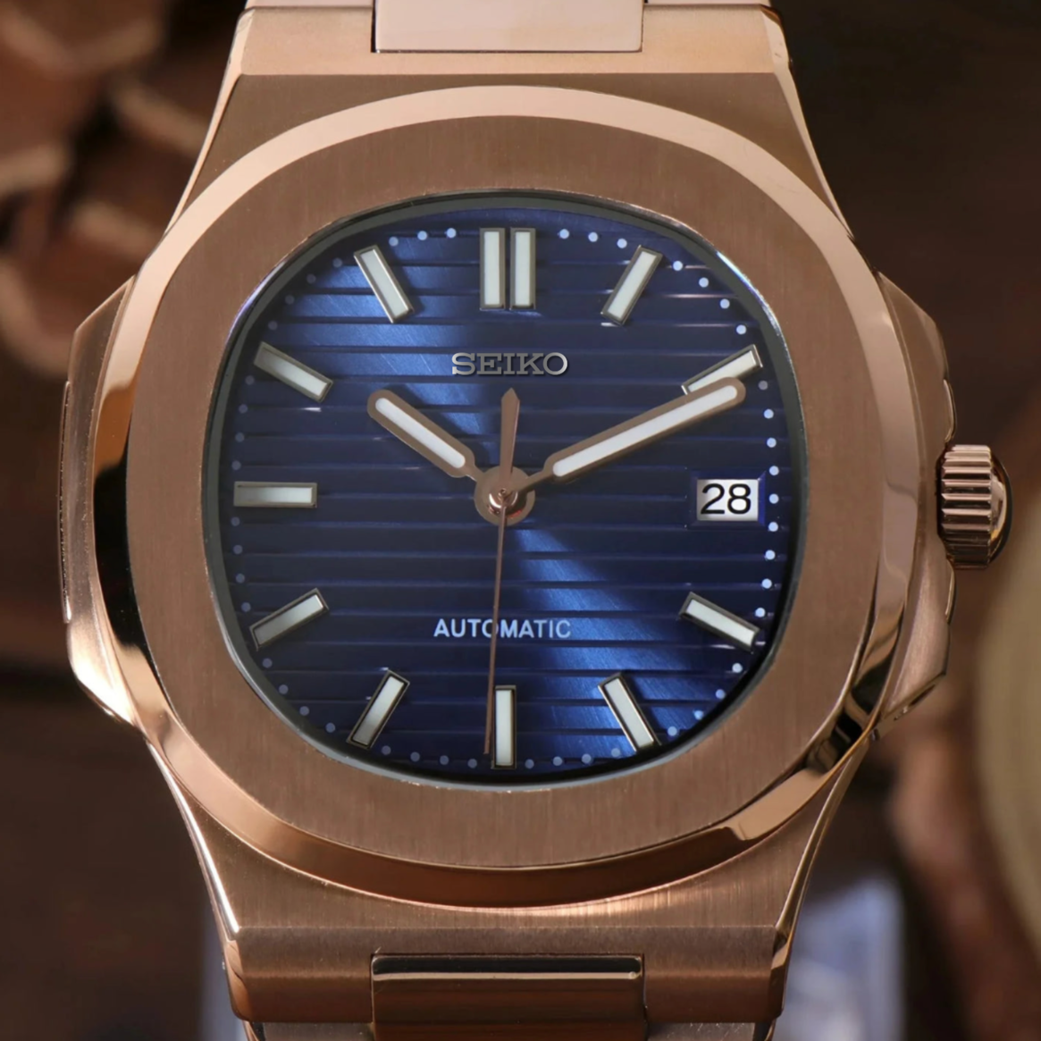 Close up of Seiko mod Nautilus rose gold royal blue dial featuring horizontal pattern and applied indices