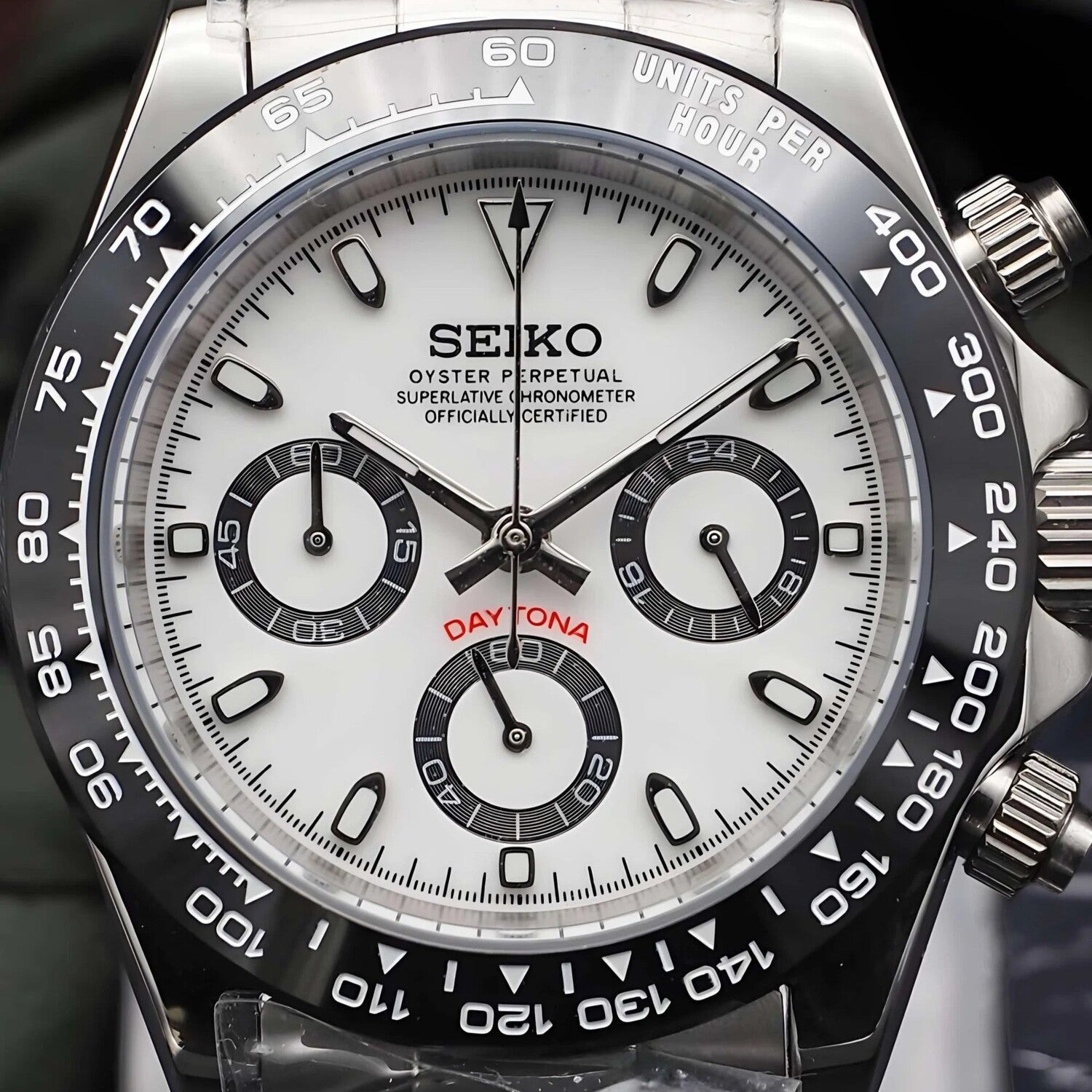 Close up of Seiko Mod Daytona Panda dial with white face, black subdials, red Daytona text and ceramic tachymeter bezel.