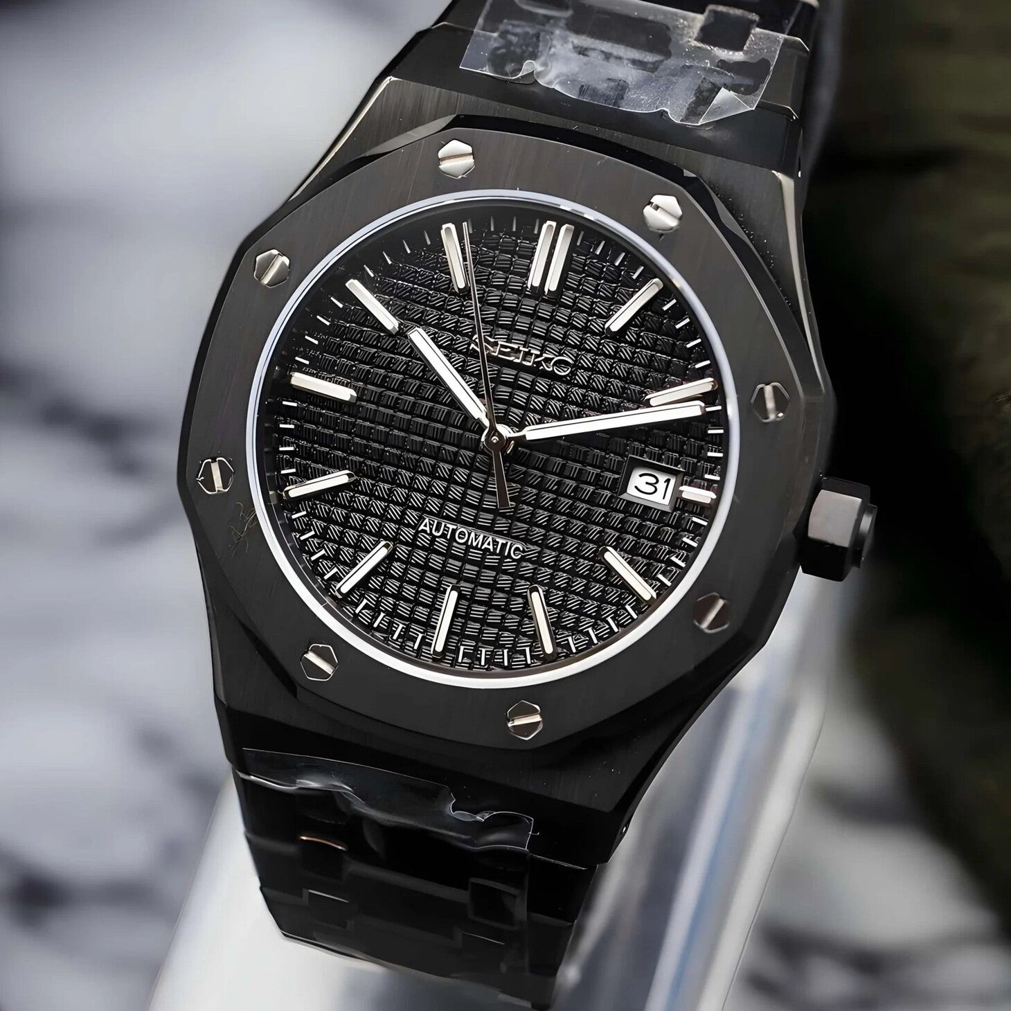 Right angled view of the Seiko Mod Royal Oak automatic watch in all black with a waffle pattern dial, polished indices, brushed stainless steel case, and integrated bracelet