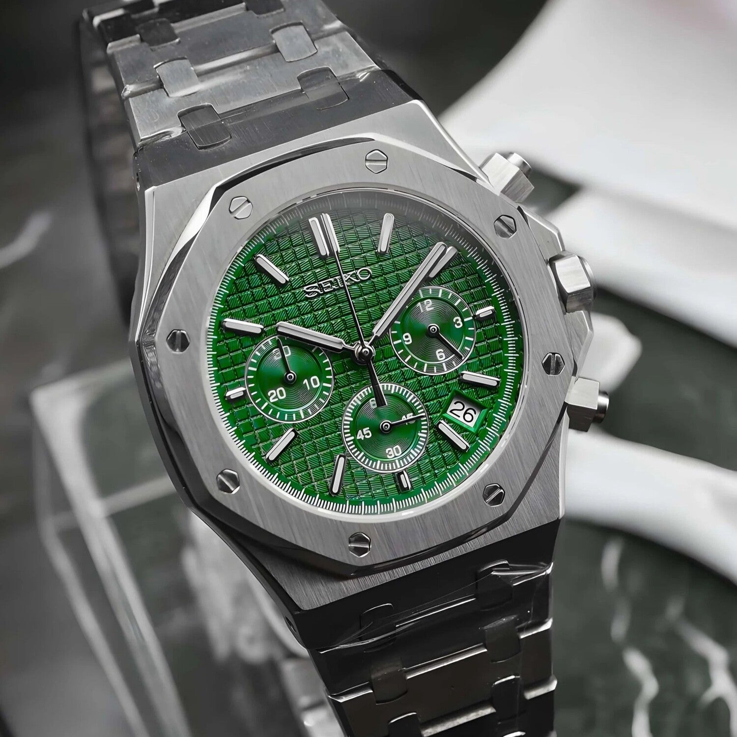 Right angled close up view of the Seiko Mod Royal Oak chronograph with vivid green waffle textured dial, three matching green subdials, brushed stainless steel case, polished bezel screws, and integrated steel bracelet.