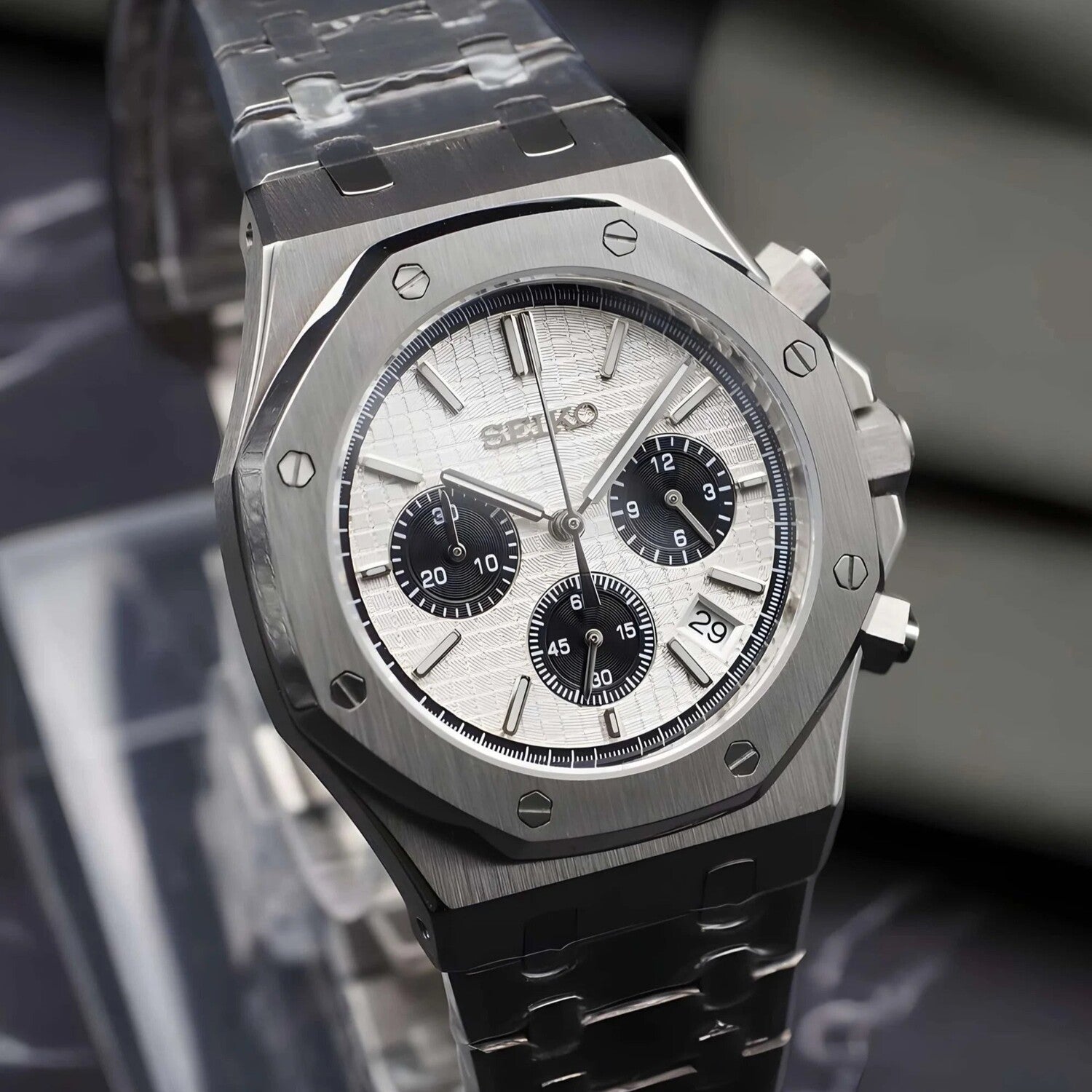 Right angled view of the Seiko Mod Royal Oak Panda chronograph showcasing a white patterned dial with black subdials, brushed 316L stainless steel octagonal bezel with exposed screws, steel bracelet, and date display near 4 o’clock.