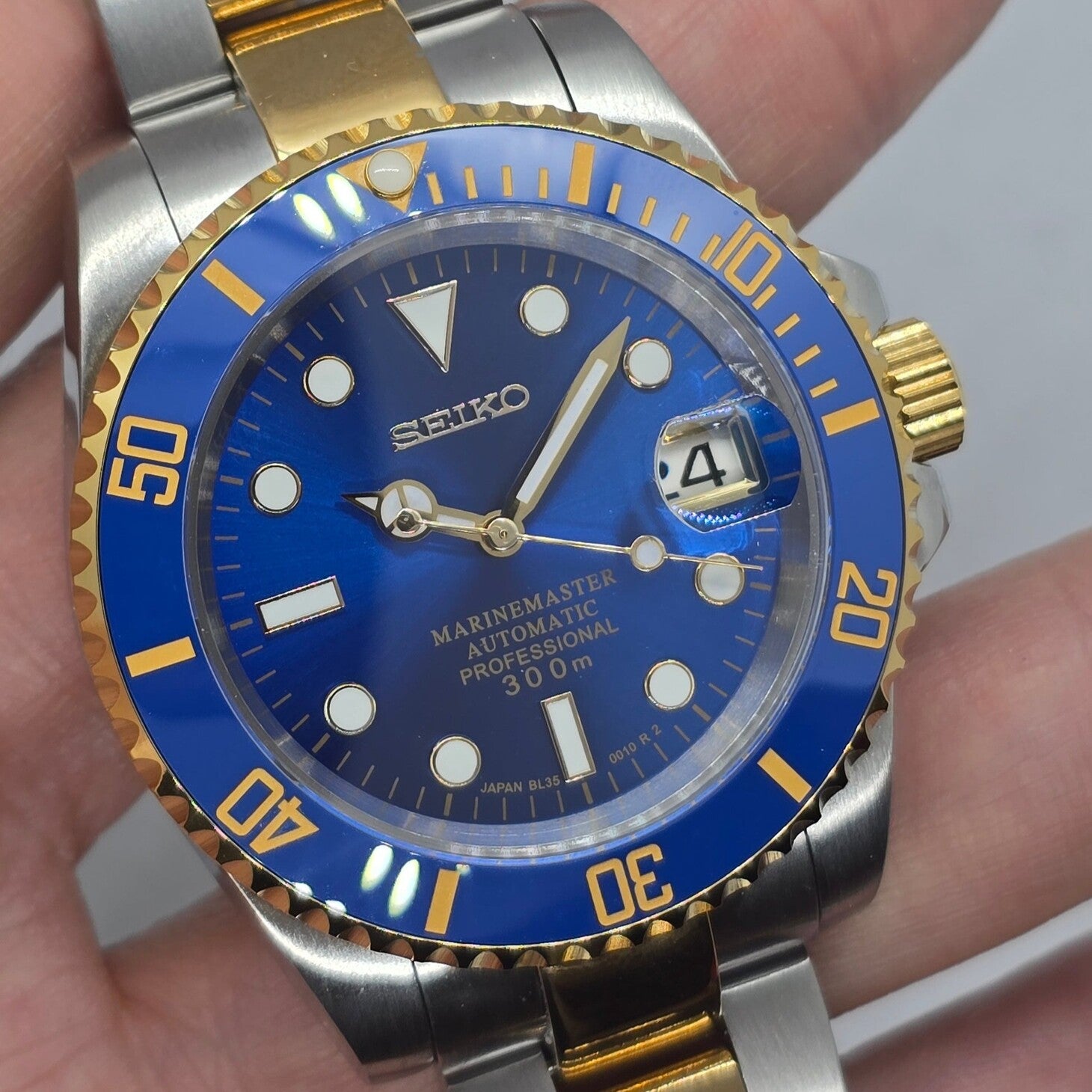 Angled close view Seiko Mod Submariner blue face with gold bezel and luminous markers