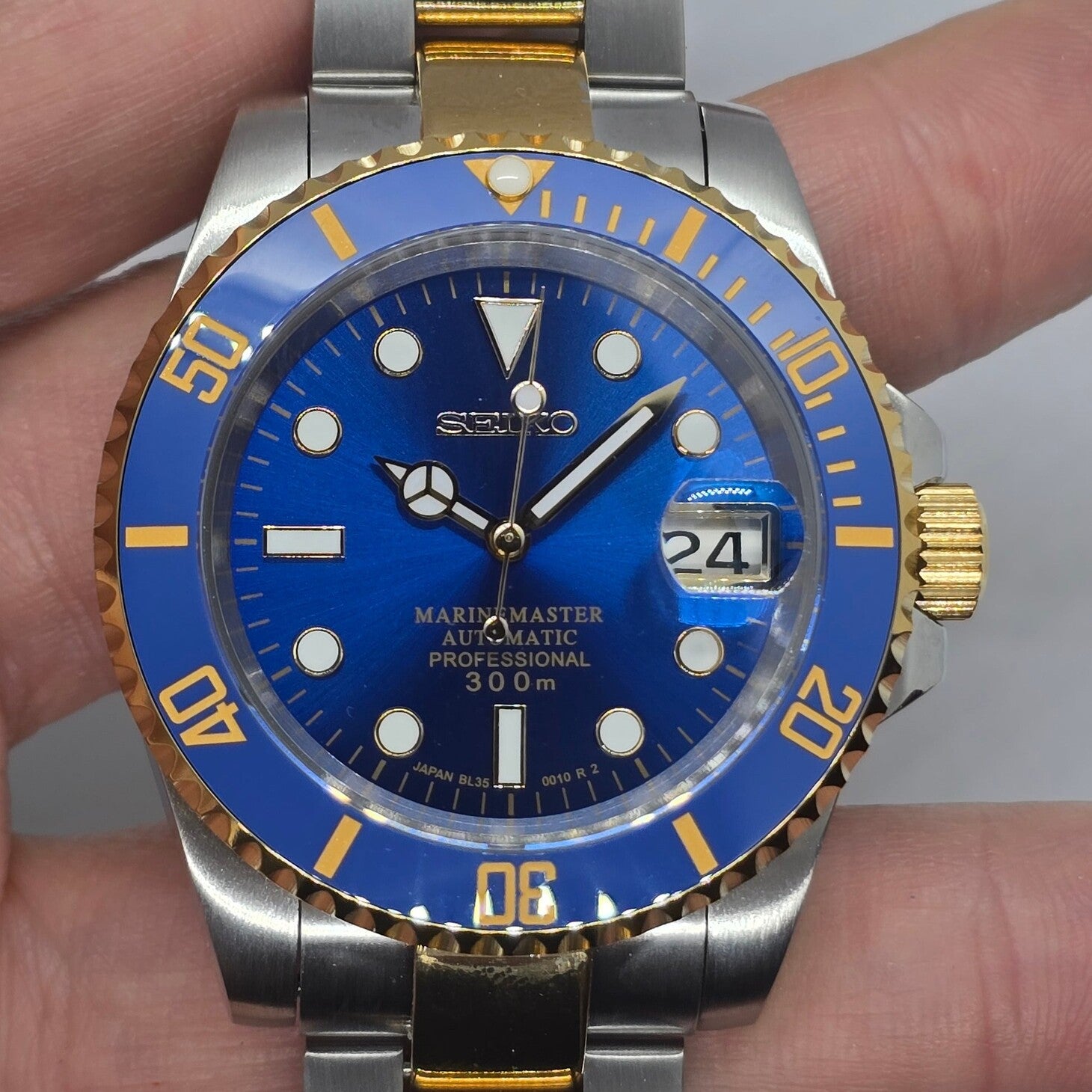 Close front view Seiko Mod Submariner blue dial magnified date and gold bezel detail