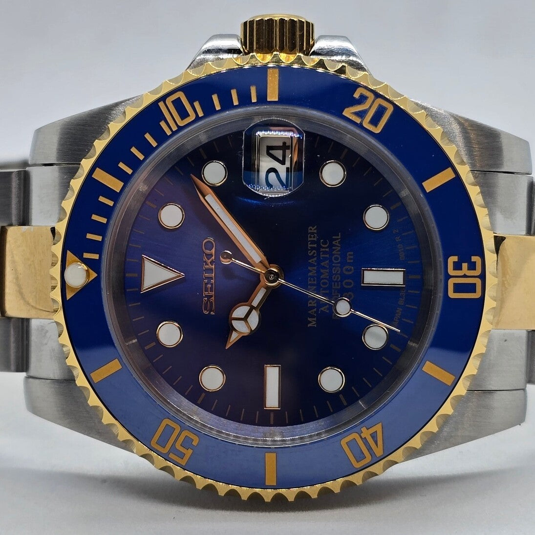 Horizontal close view Seiko Mod Submariner gold bezel edge blue Dial Two Tones and bracelet reflection