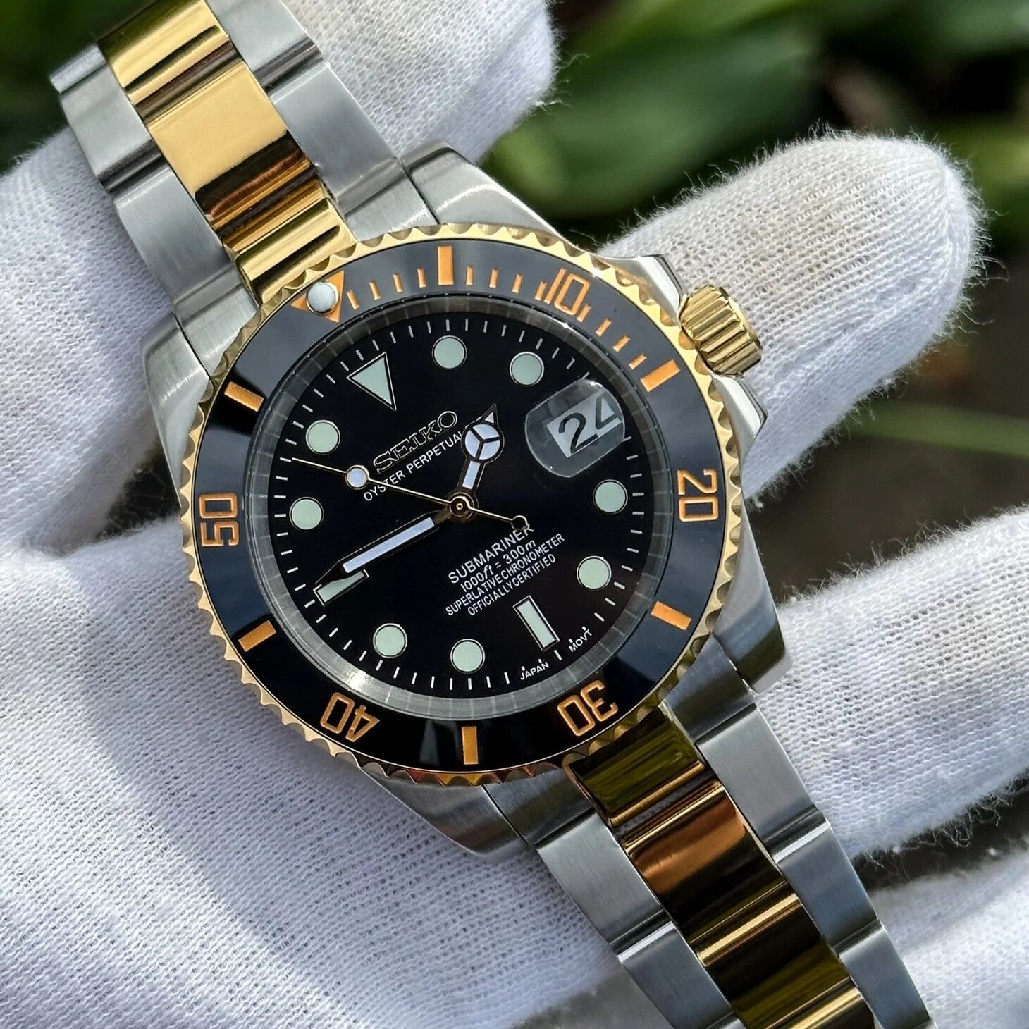 Angled front view Seiko Mod Submariner black dial gold bezel on white glove outdoors