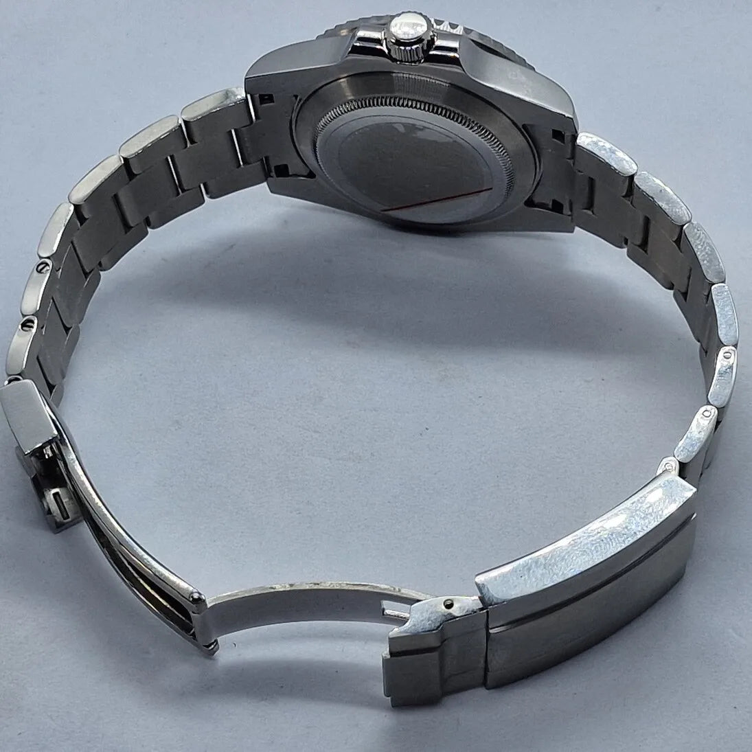 Rueckansicht der Seiko Mod Submariner Kermit mit geoeffnetem Edelstahlarmband. Das Bild zeigt den verschraubten Gehaeuseboden und die massive Verarbeitung der automatischen Taucheruhr.