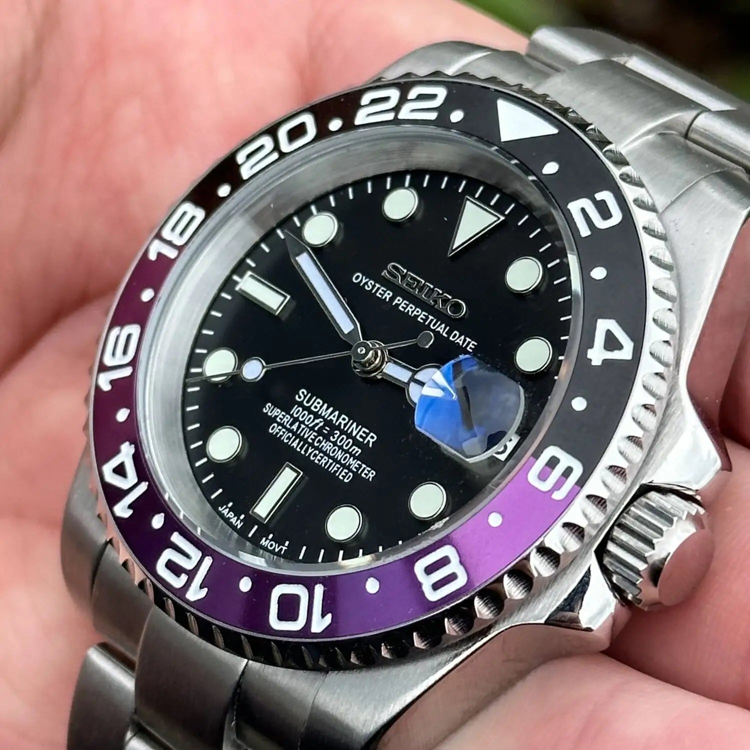 Nahaufnahme der Seiko Mod GMT Joker mit lila-schwarzer GMT-Lünette und Edelstahlgehäuse in der Hand