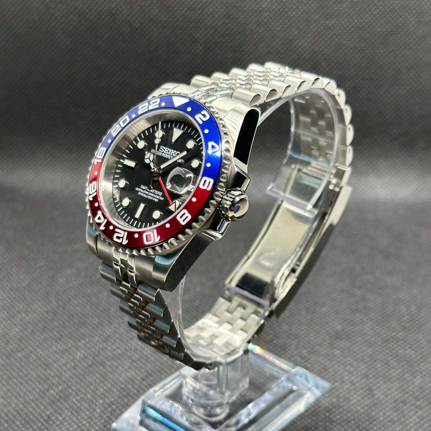 Seiko Mod GMT Pepsi Schrägansicht mit NH34 GMT Uhrwerk, blau-roter Keramiklünette, Jubilee Edelstahlarmband, Display Stand