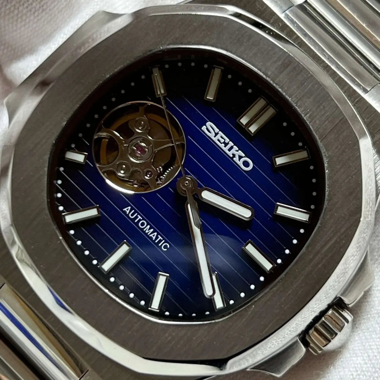 Nahaufnahme der Seiko Mod Royal Blue mit skelettiertem Zifferblatt und silbernen Indizes und Open-Heart-Design