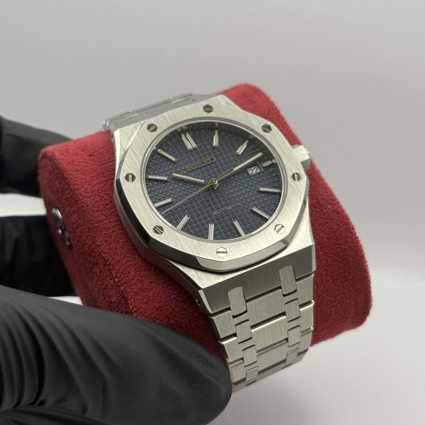 Seitenperspektive der Seiko Mod Royal Oak Blue mit navyblauem Zifferblatt, Edelstahlarmband auf rotem Kissen