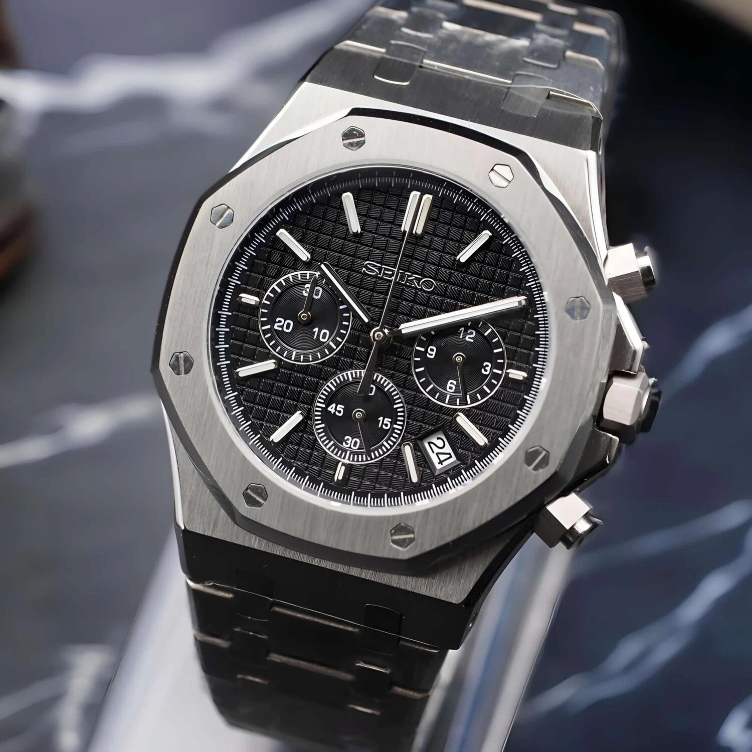 Seitliche Nahaufnahme der Seiko Mod Royal Oak Chrono Black mit schwarzem Zifferblatt, gebürstetem Edelstahlgehäuse und Datumsanzeige bei 4 Uhr