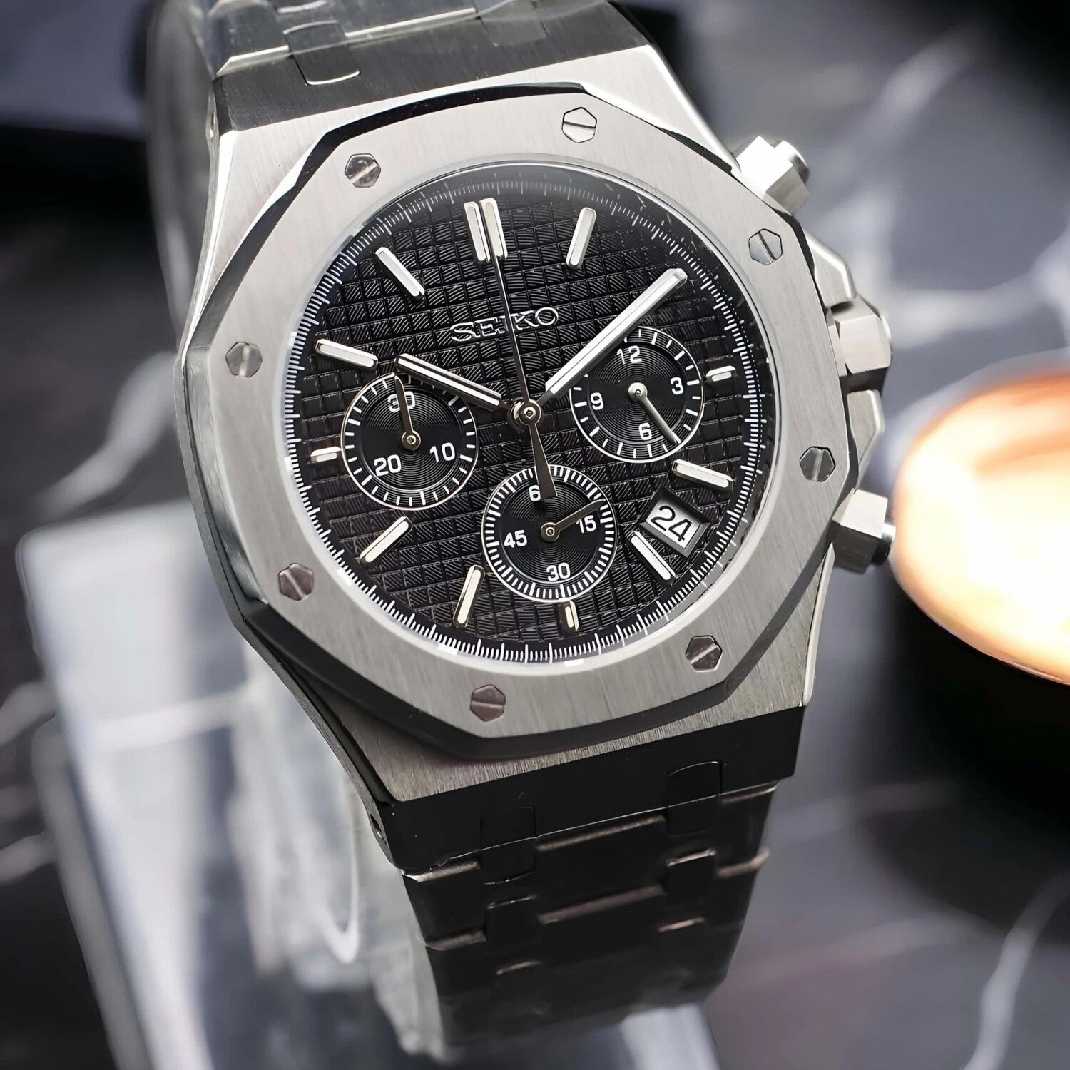 Nahaufnahme der Seiko Mod Royal Oak Chrono Black mit schwarzem Waffle-Zifferblatt, drei Subdials und Datumsanzeige bei 10 Uhr