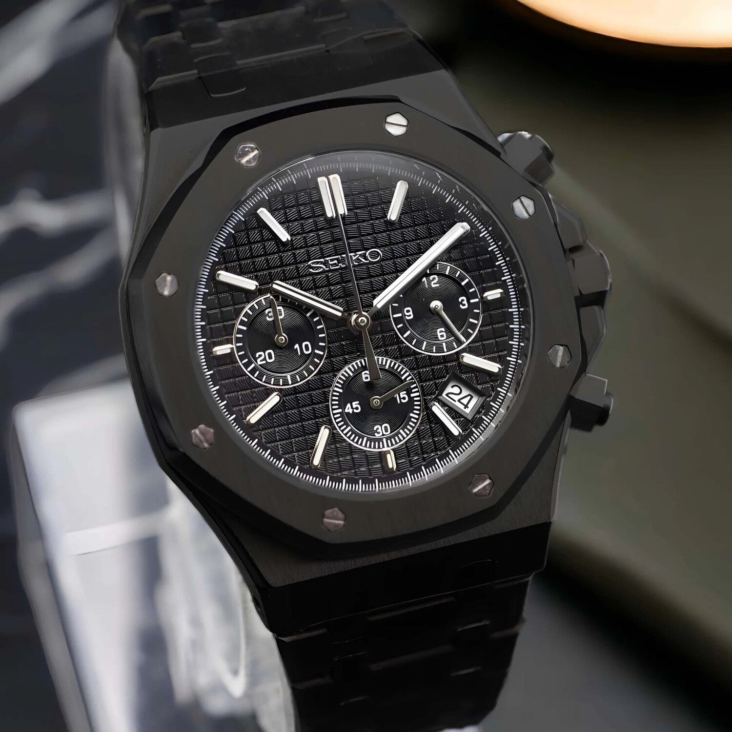 Seitenansicht der Seiko Mod Royal Oak Chrono Triple Black mit gebürstetem schwarzem Edelstahlgehäuse, markanten Chronograph-Drückern und integriertem Armband