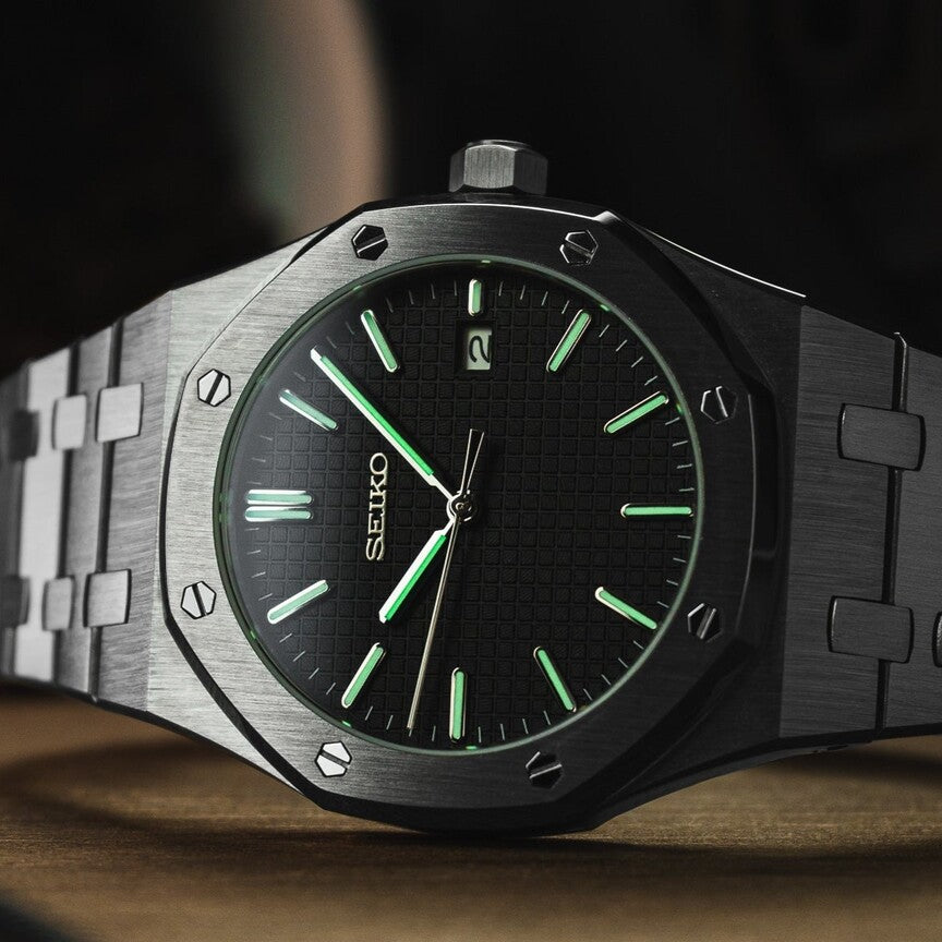 Nahaufnahme der Seiko Mod Royal Oak Green mit leuchtenden grünen Indizes auf schwarzem Zifferblatt bei Dunkelheit