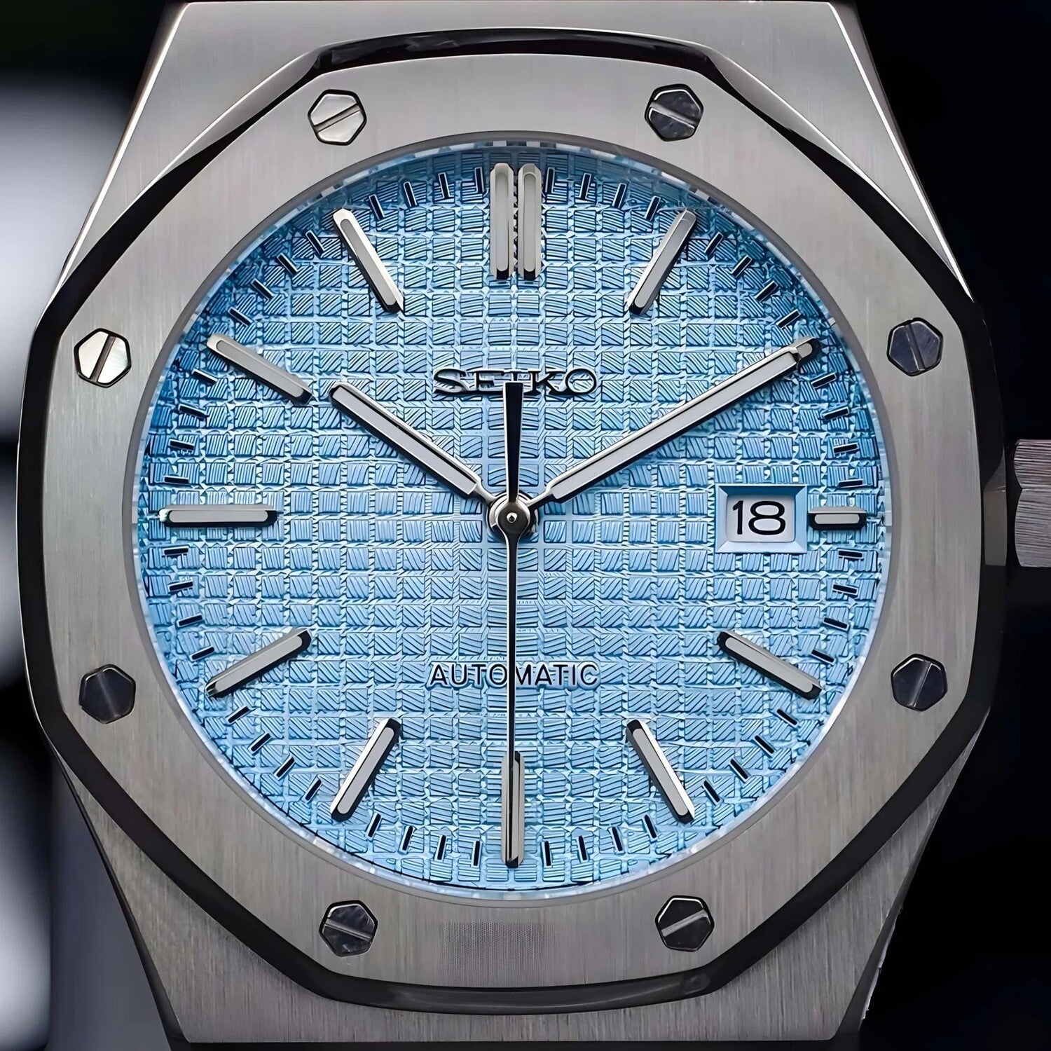 Detailaufnahme des Seiko Mod Royal Oak Ice Blue Zifferblatts mit strukturiertem Muster, leuchtenden Indizes und Datumsanzeige bei 3 Uhr