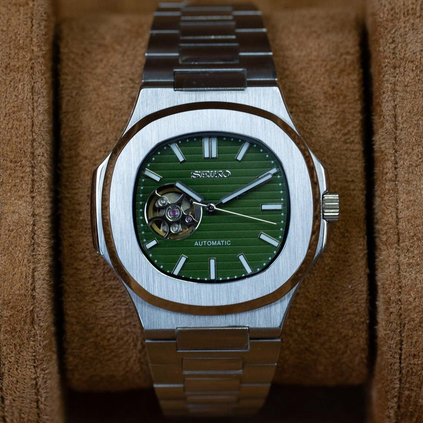 Front view of Seiko mod Nautilus olive green open heart displayed on brown suede background