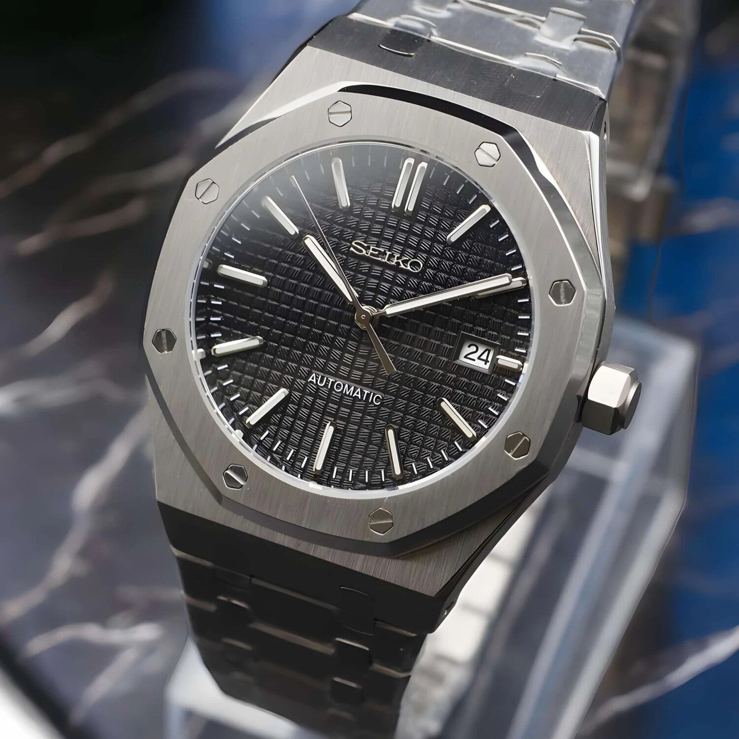 Side-angled view of the Seiko Mod Royal Oak automatic watch with black grid-pattern dial, brushed stainless steel case, and steel bracelet featuring a butterfly clasp