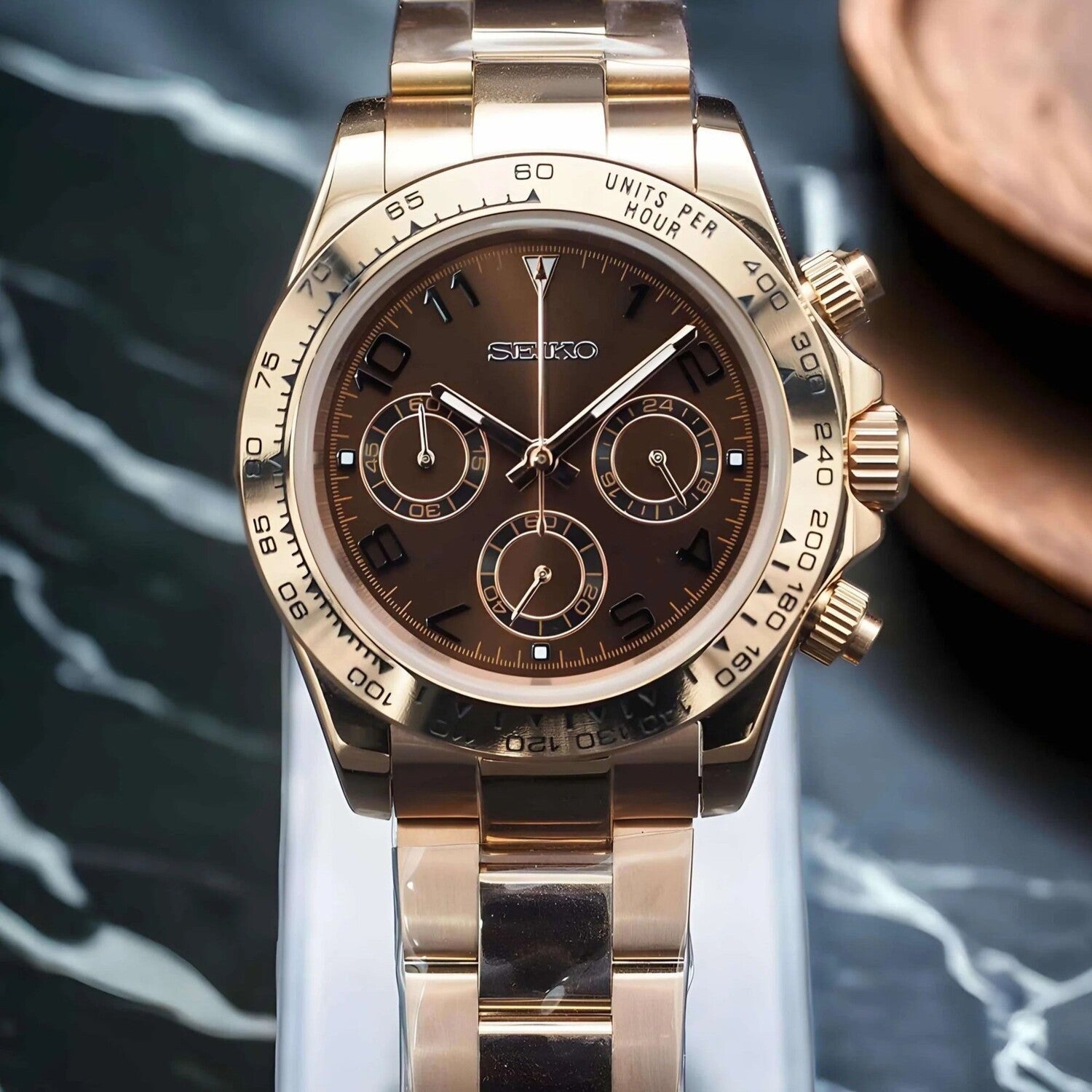 Seiko Mod Daytona Rose Gold Chocolate Chronograph Luxusuhr mit Chocolate-Zifferblatt, Roségold-Gehäuse, schwarzer Keramik-Lünette, Oyster-Armband und VK63 Uhrwerk auf Marmor