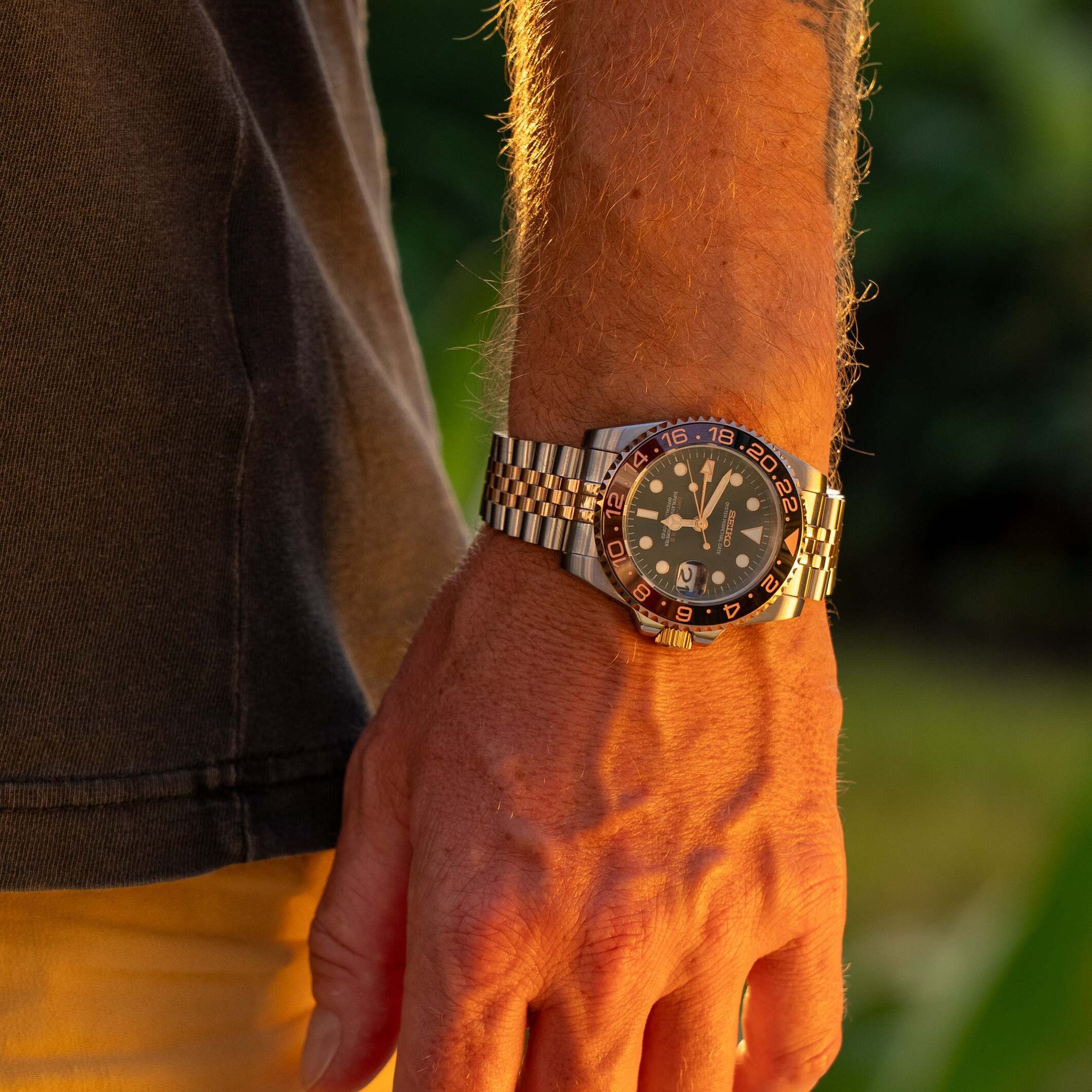 Seiko Mod GMT Rootbeer Outdoor Aufnahme, warme Roségold Highlights, schwarzes Zifferblatt Kontrast, Jubilee Armband, Dual-Time