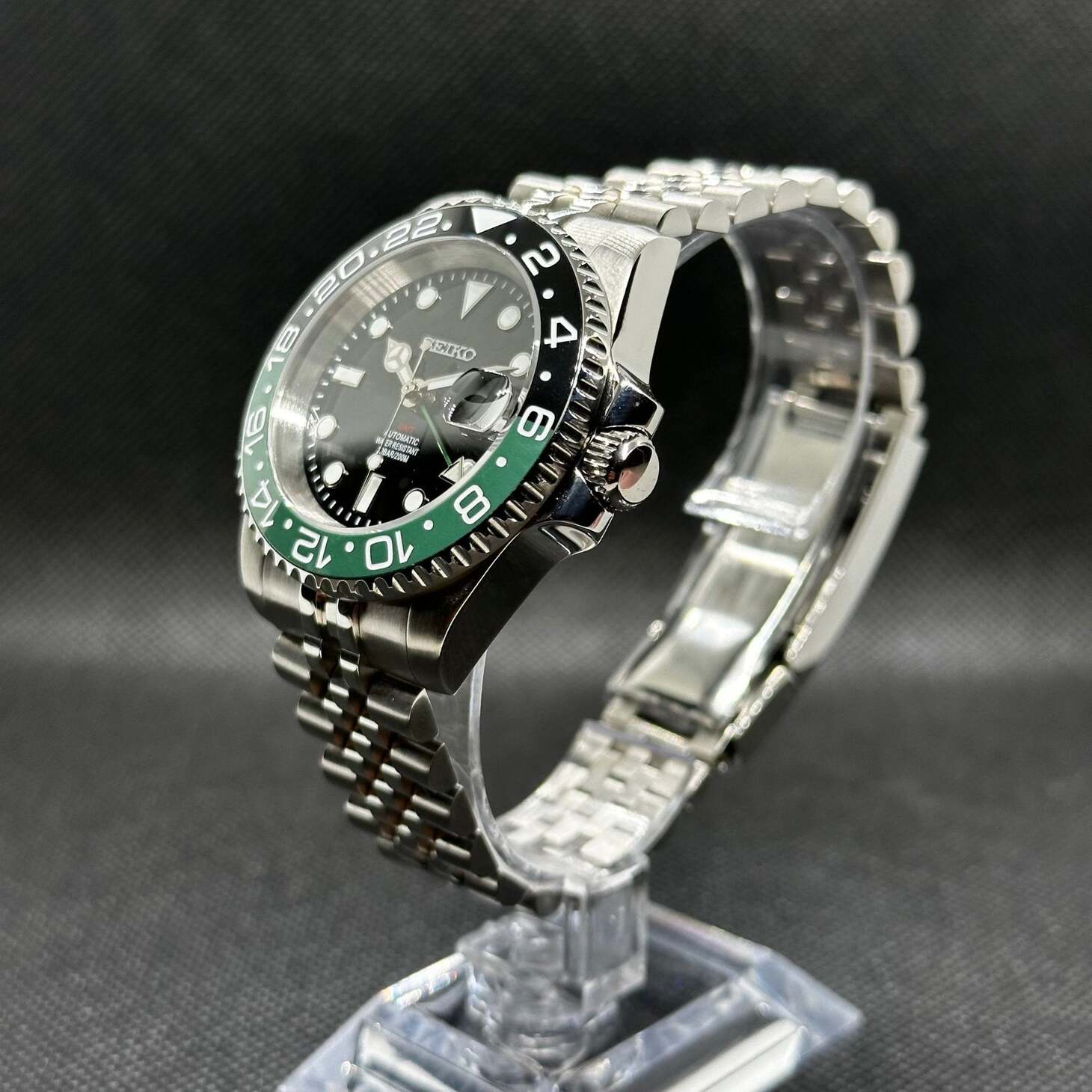 Seiko Mod GMT Sprite Schrägansicht mit polierter Krone, grün-akzentuierter Lünette und GMT-Funktion