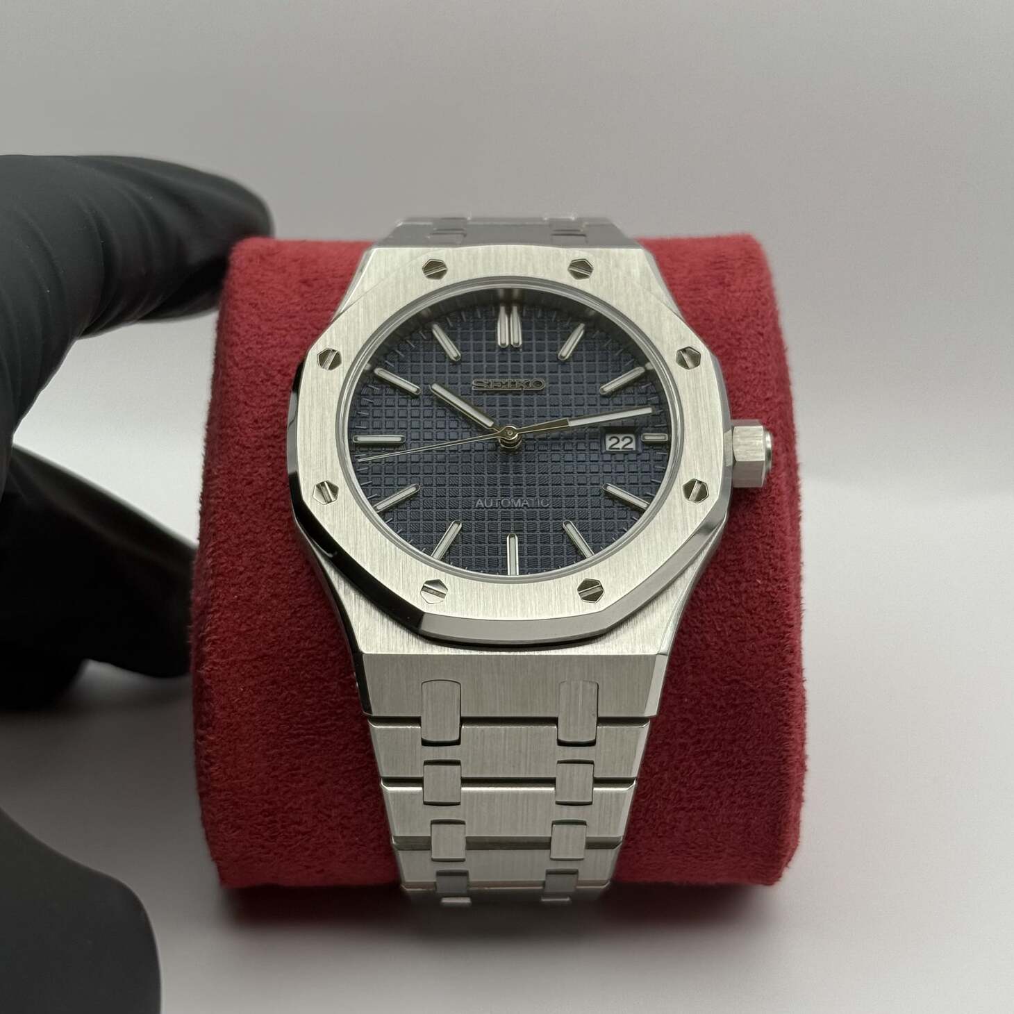 Frontansicht der Seiko Mod Royal Oak Blue mit dunkelblauem Grid-Zifferblatt, Edelstahlarmband und Datumsfenster auf rotem Kissen