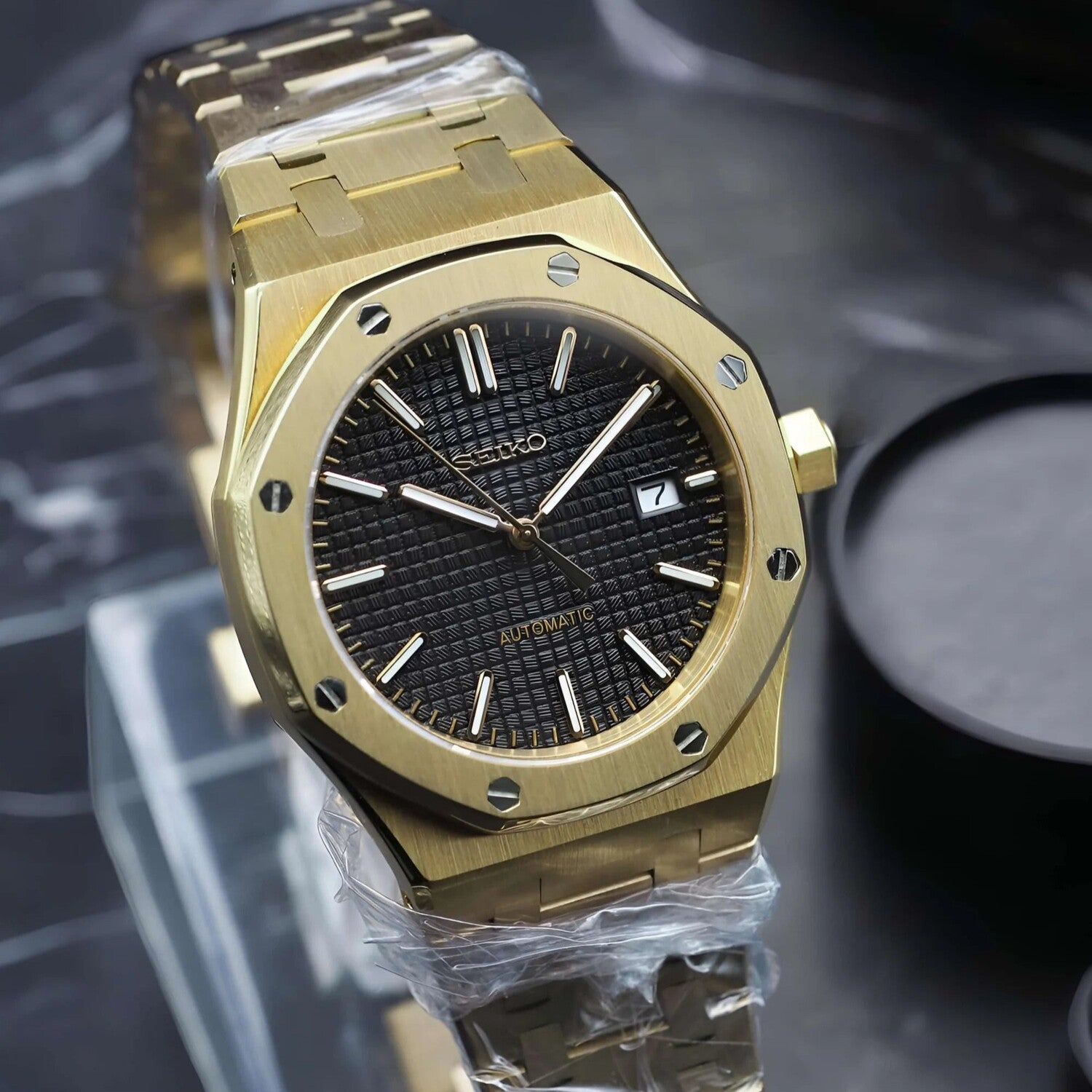 Linke Schrägansicht der Seiko Mod Royal Oak Yellow Gold Black mit strukturiertem schwarzem Zifferblatt, polierten Zeigern und achteckiger Goldlünette