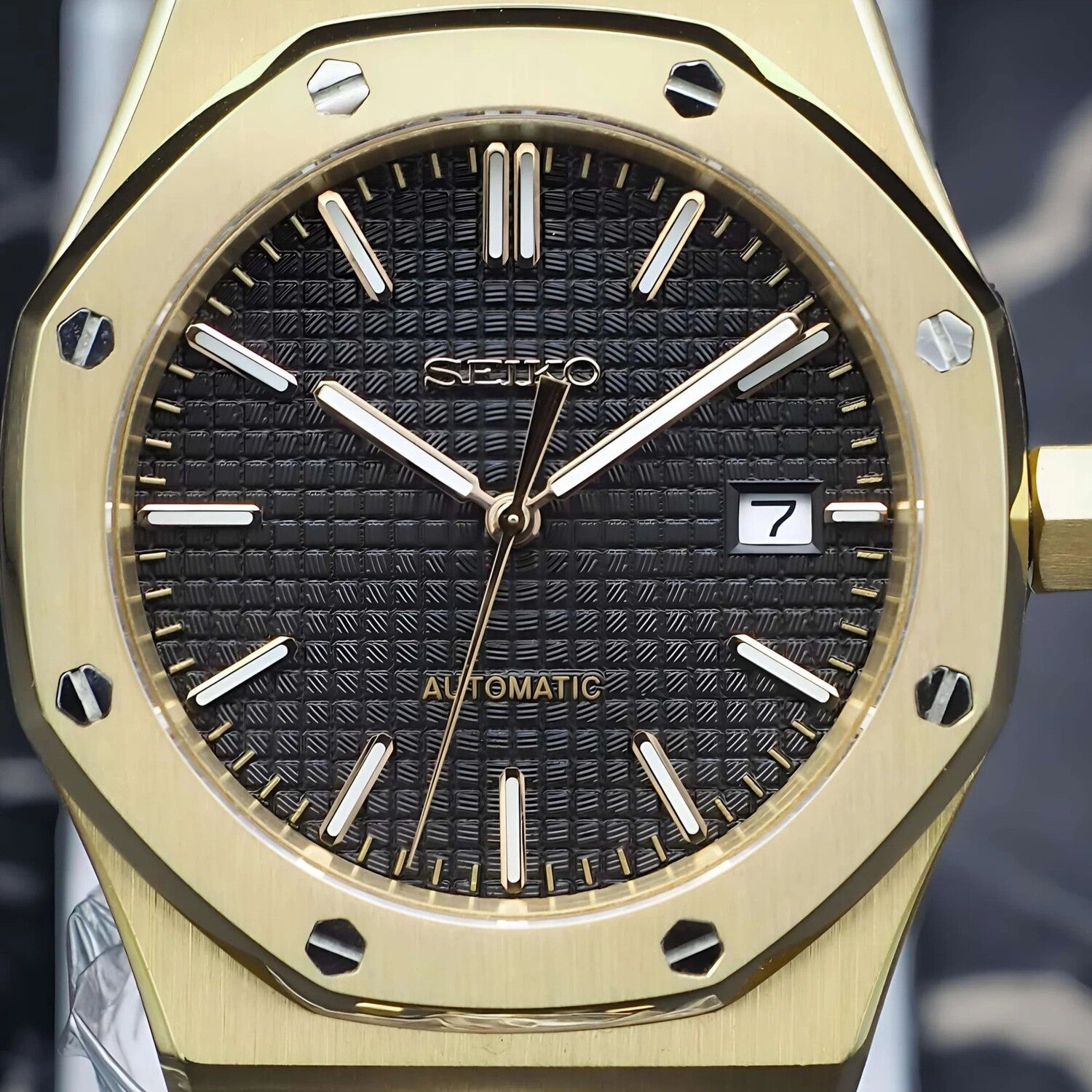 Nahaufnahme des Seiko Mod Royal Oak Yellow Gold Black Zifferblatts mit schwarzem Waffle-Muster, goldenen Zeigern und Datumsanzeige bei 3 Uhr