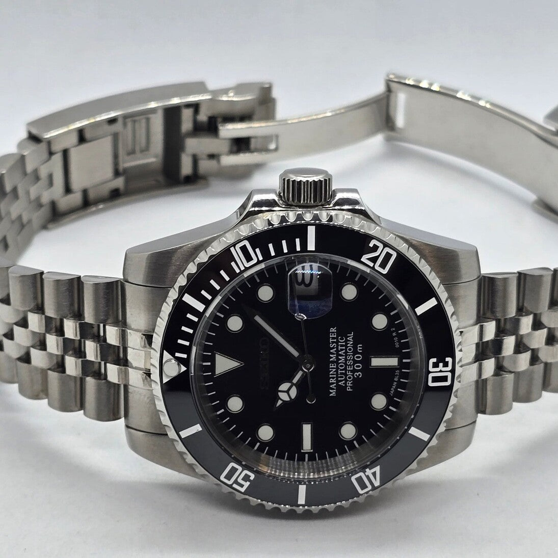 Seiko Mod Submariner Classic Black horizontale Ansicht mit geöffnetem Armband und Gehäuse Reflektion